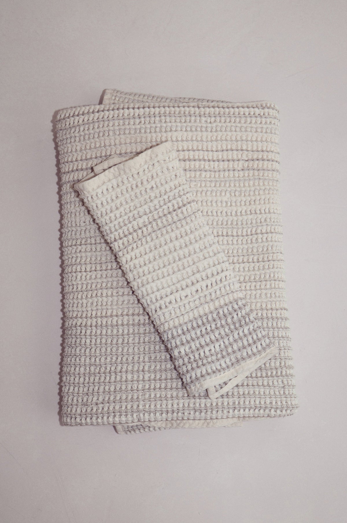 Sand-colored cotton receiving baby towel set folded neatly on a neutral surface