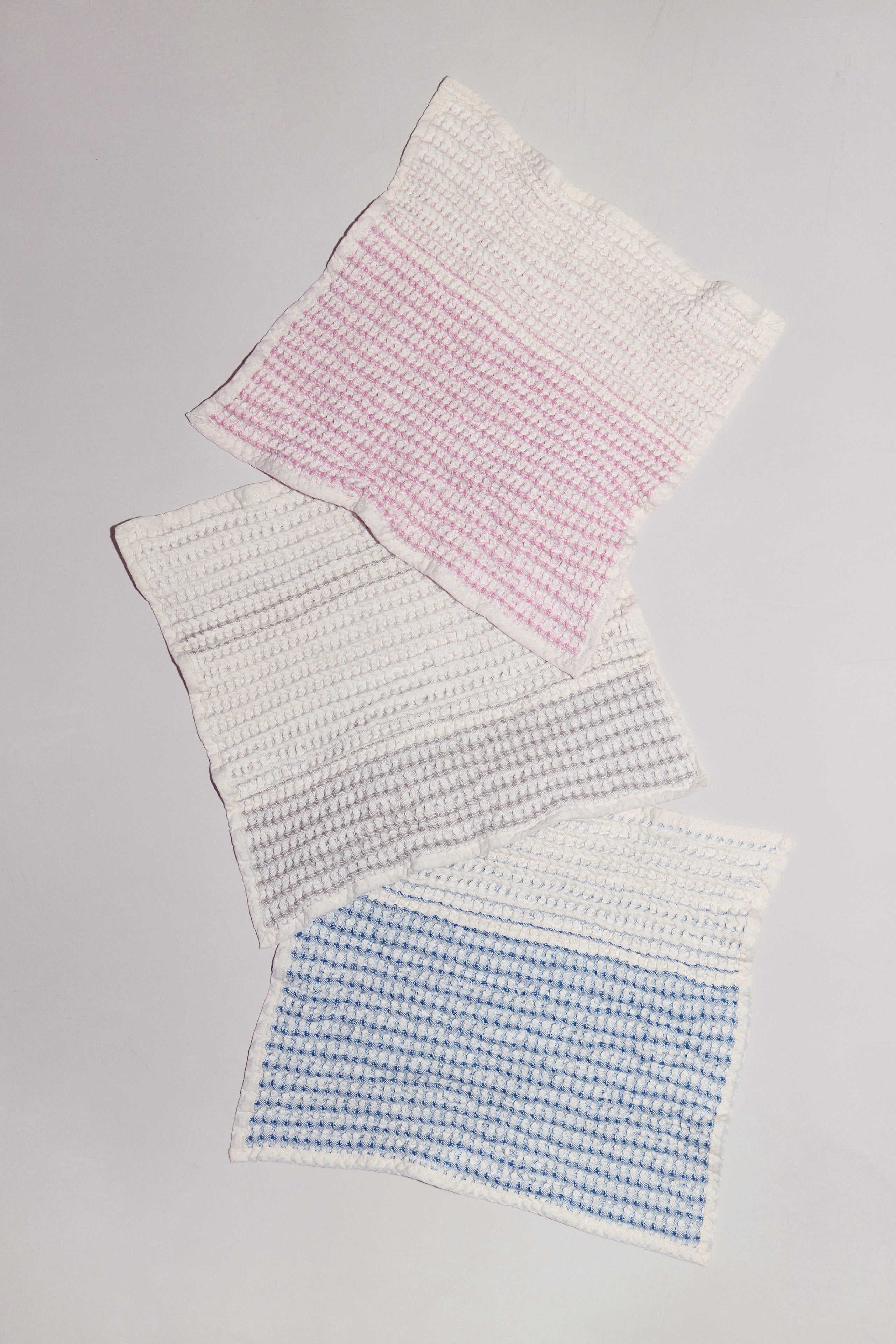 Sand, Shell, and Tide baby washcloths laid flat showing available colors and natural form