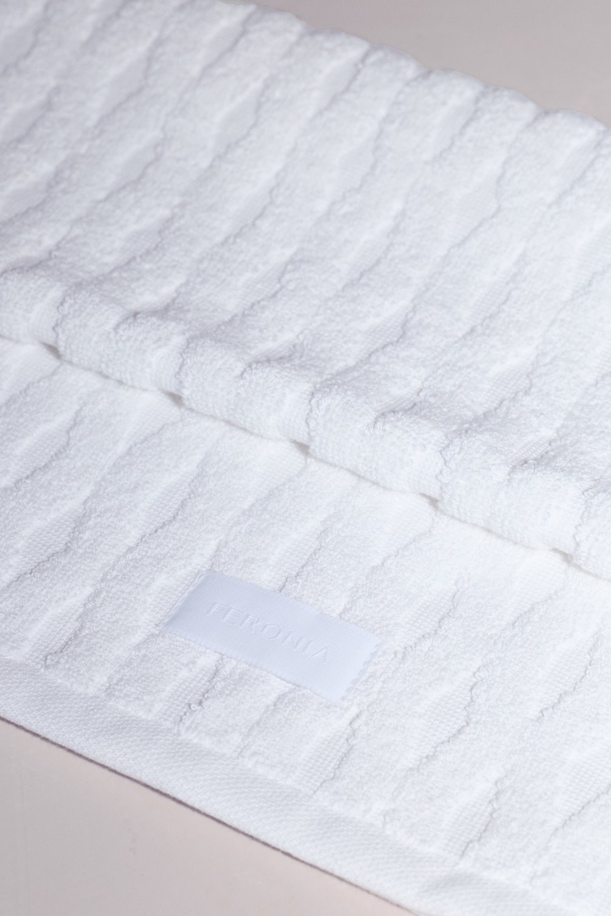 Detailed close-up of hem finish, lable, and cotton-linen terrycloth weave on Ellipse bath towel