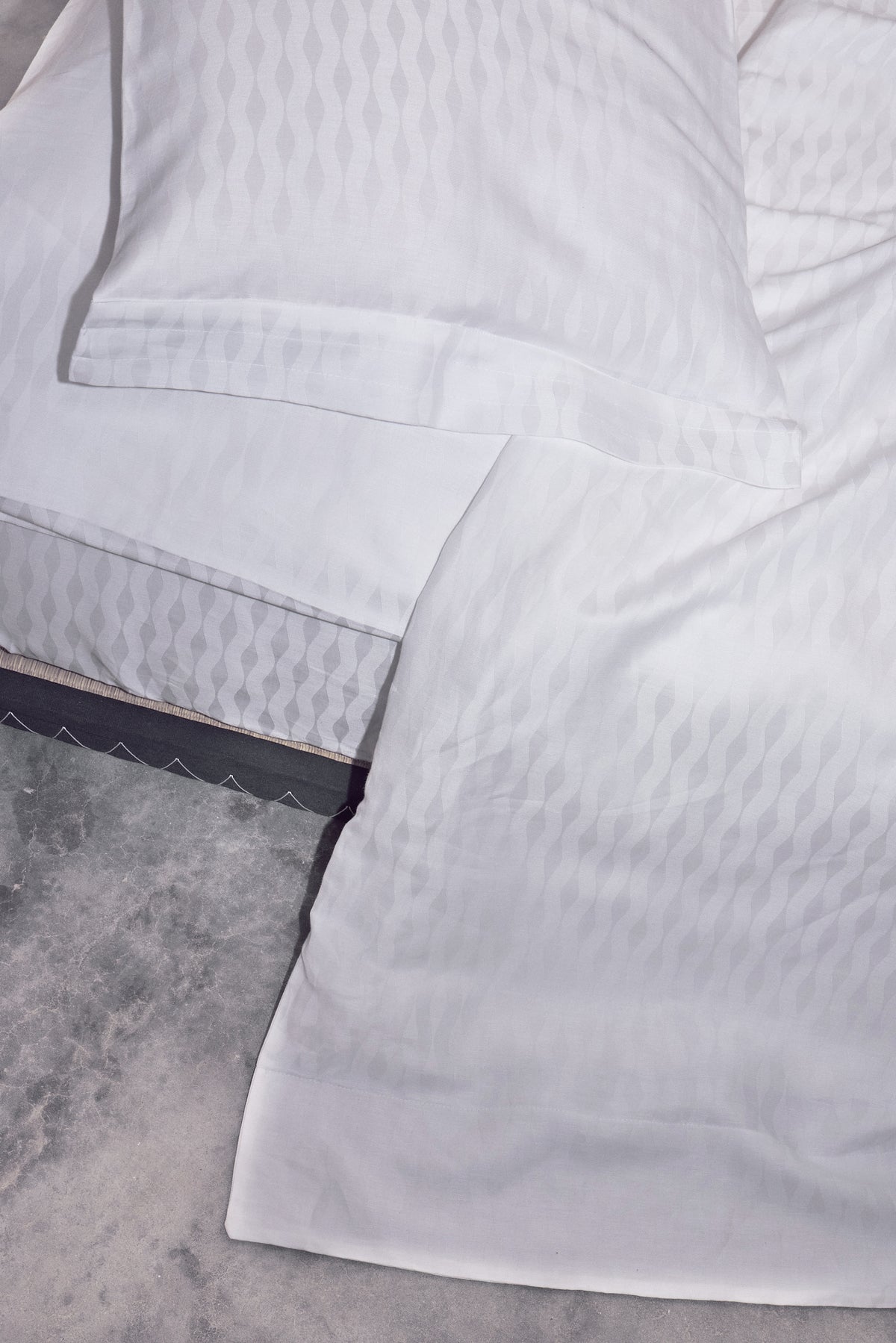 White mineral close up dtailed shot of corner duvet, sham flange and fitted ellipse sheet