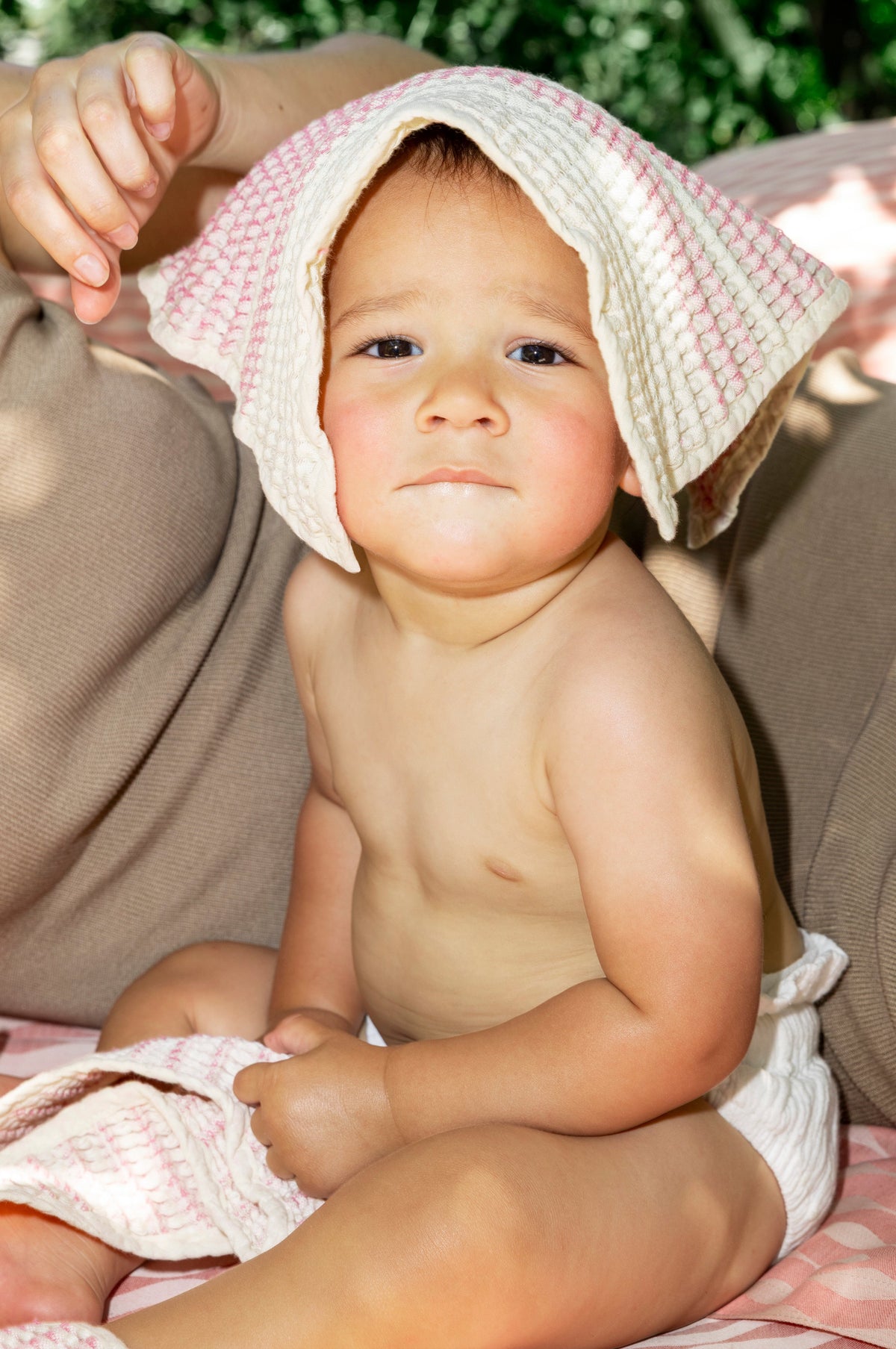 Lifestyle shot of baby with Shell cotton washcloth draped over his head